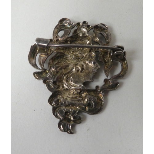 4 - An Art Nouveau white metal brooch, fashioned as a woman's head with flowing hair