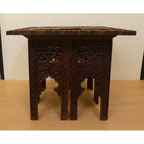 59 - An Anglo-Indian carved hardwood table with a sectional underframe, supporting a profusely decorated,... 