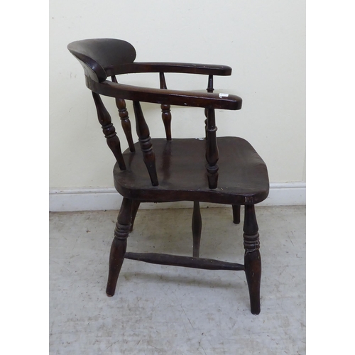 102 - An early 20thC and later overpainted oak framed a captain's desk chair, the solid seat raised on rin... 