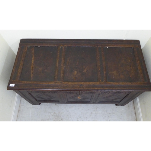 134 - A late 18thC panelled oak coffer with straight sides and a hinged lid, raised on square legs  2... 