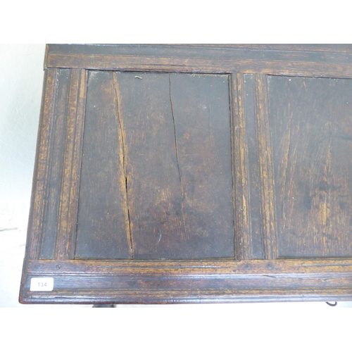 134 - A late 18thC panelled oak coffer with straight sides and a hinged lid, raised on square legs  2... 