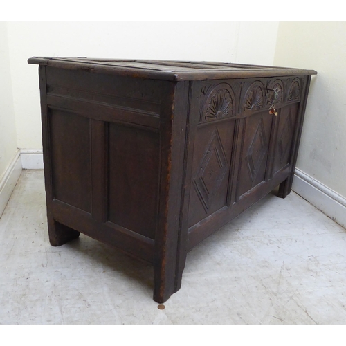 134 - A late 18thC panelled oak coffer with straight sides and a hinged lid, raised on square legs  2... 