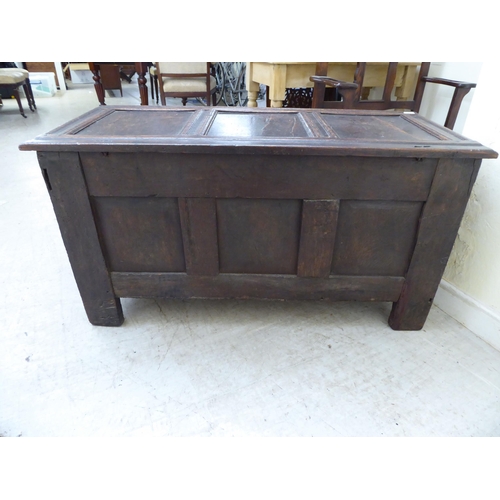 134 - A late 18thC panelled oak coffer with straight sides and a hinged lid, raised on square legs  2... 