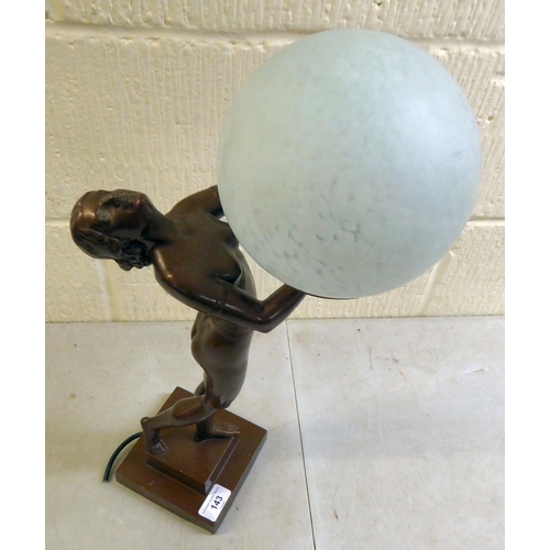 143 - A modern reproduction of an Art Deco inspired bronze table lamp, fashioned as a nude, holding a sphe... 