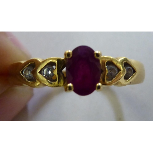 371 - A yellow metal ring, set with a central ruby, flanked by four diamonds  stamped 750