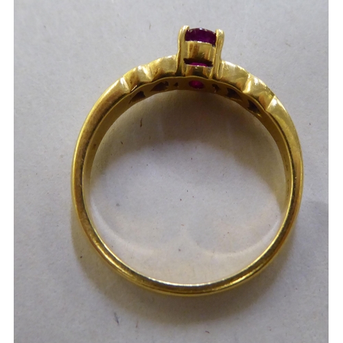 371 - A yellow metal ring, set with a central ruby, flanked by four diamonds  stamped 750