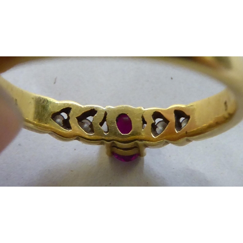 371 - A yellow metal ring, set with a central ruby, flanked by four diamonds  stamped 750