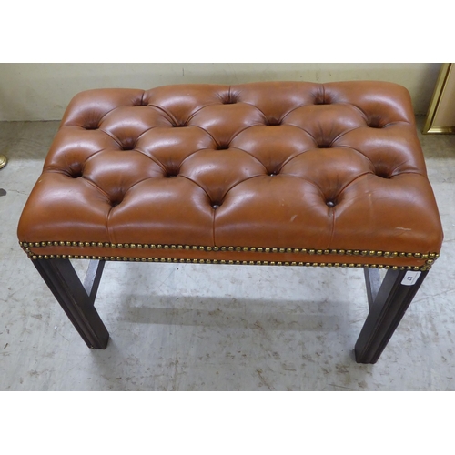 87 - A modern stool with a tan coloured button and stud upholstered, cushioned hide top, raised on straig... 