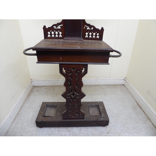 94 - A 1920s oak hallway hat/stickstand with a shield shaped mirror, eight hooks and a hinged compartment... 