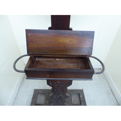 94 - A 1920s oak hallway hat/stickstand with a shield shaped mirror, eight hooks and a hinged compartment... 