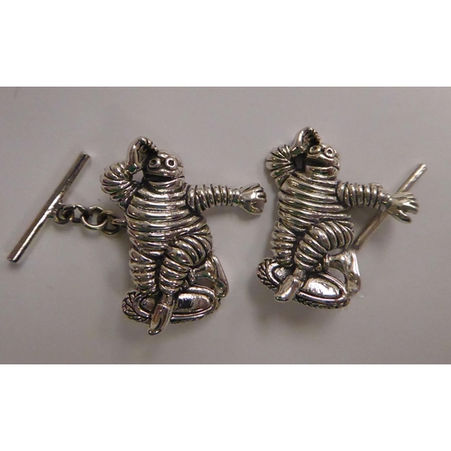 142 - A pair of Sterling silver figural, chain and tablet link cufflinks, fashioned as the Michelin Man