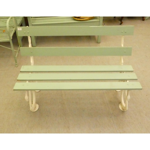 202 - A white painted cast iron, serpent design, framed garden bench with green painted slats  47