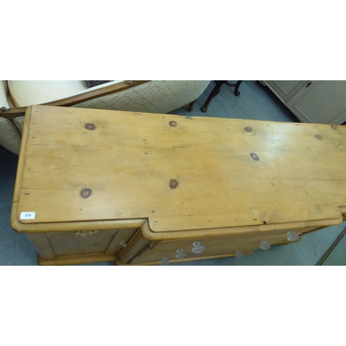 218 - An early 20thC pine breakfront sideboard with three central drawers, flanked by cupboard doors, on t... 