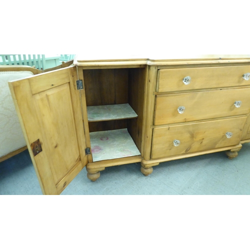 218 - An early 20thC pine breakfront sideboard with three central drawers, flanked by cupboard doors, on t... 