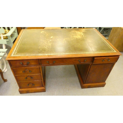 221 - A 20thC yewwood partner's desk with an arrangement of cupboard doors and drawers, on a plinth  ... 