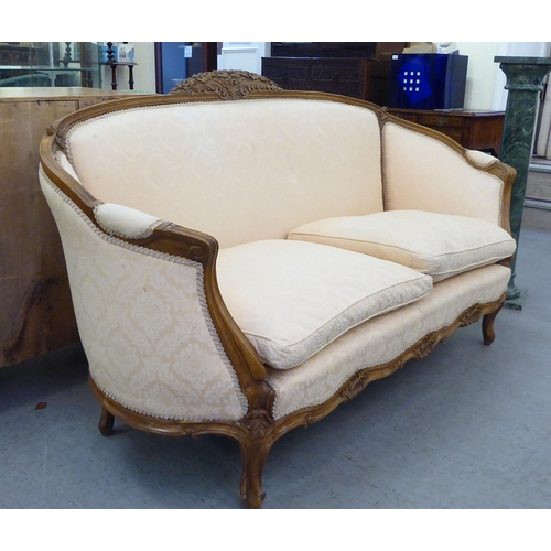 224 - A 20thC French style stained and foliate carved, beech showwood framed carved back salon settee, uph... 