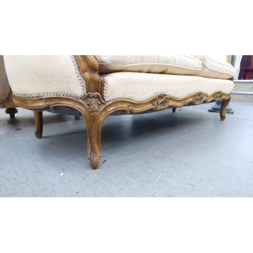 224 - A 20thC French style stained and foliate carved, beech showwood framed carved back salon settee, uph... 