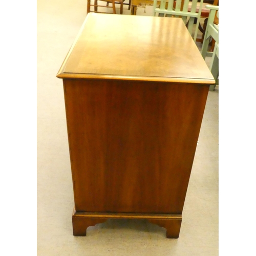 228 - A 20thC quarter walnut veneered and crossbanded, mahogany four drawer dressing chest, raised on brac... 