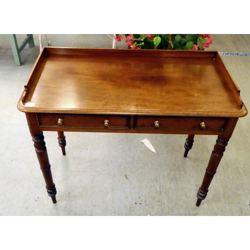 231 - An Edwardian mahogany two drawer writing table, raised on turned legs  32