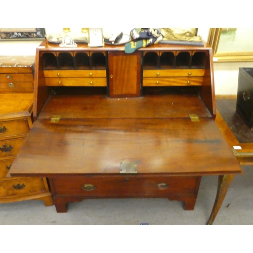 243 - A George III mahogany bureau, the fall flap over four long, graduated drawers, raised on bracket fee... 