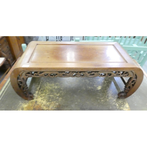 250 - An early/mid 20thC Chinese fruitwood coffee table with a carved and C-scrolled frieze, raised on car... 