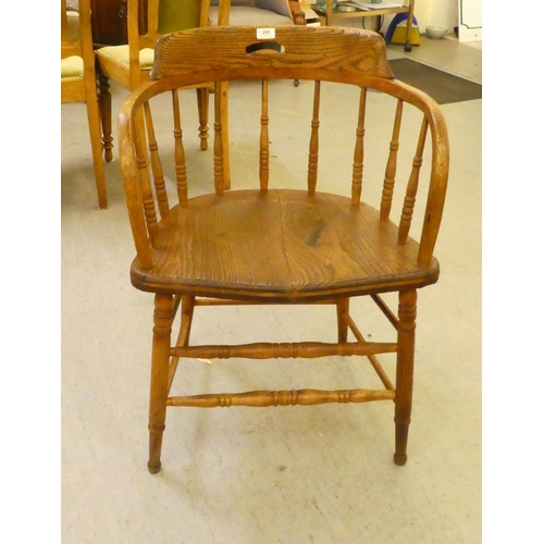 269 - An early 20thC oak framed captains chair with a spindle turned back and solid seat, raised on turned... 