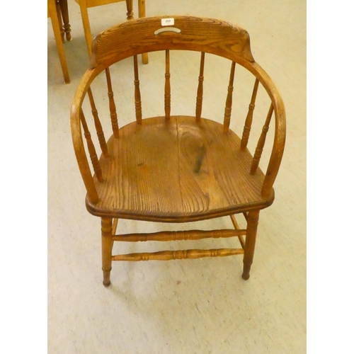 269 - An early 20thC oak framed captains chair with a spindle turned back and solid seat, raised on turned... 