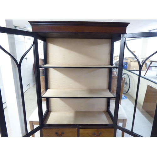 42 - A 1930s mahogany finished display cabinet with a pair of glazed doors, over two in-line drawers, rai... 