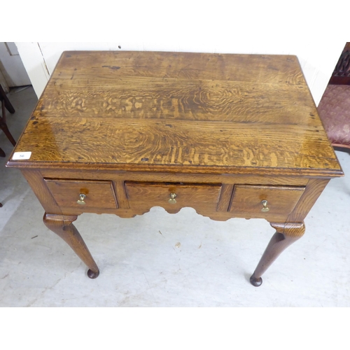 56 - A George III oak three drawer lowboy, raised on turned legs  29