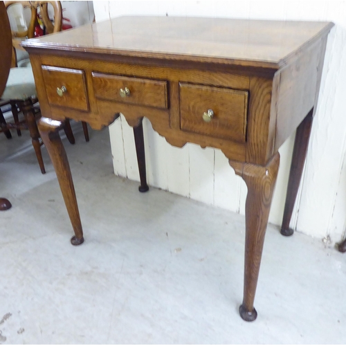 56 - A George III oak three drawer lowboy, raised on turned legs  29