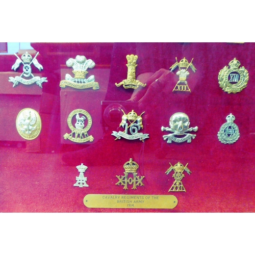 120 - A framed and glazed display of thirty British Army Cavalry regimental cap badges and other insignia,... 