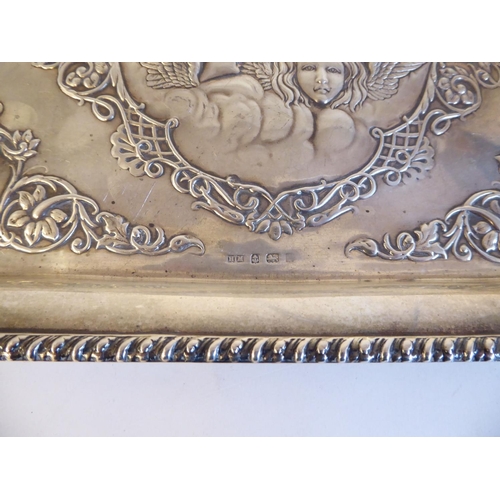 132 - A late Victorian silver dressing table tray with embossed and chased, scrolled ornament, incorporati... 