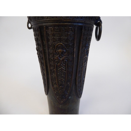 148 - A Chinese cast bronze vase of shouldered, tapered form with a narrow neck and flared rim, decorated ... 