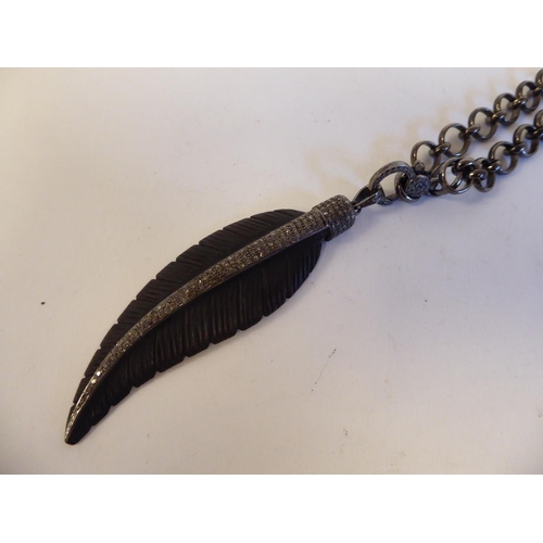 151 - A feather and diamond set pendant, on a bronze finished, ring link necklace