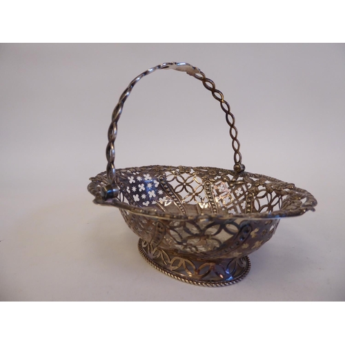 158 - A George II silver oval sweet basket with pierced, impressed ornament and a folding swing handle, on... 