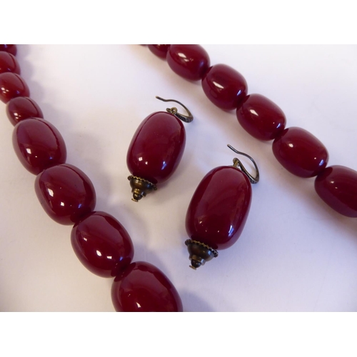 208 - A cherry coloured amber, oval graduated bead necklace with a pair of matching, oval bead pendant ear... 