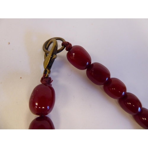 208 - A cherry coloured amber, oval graduated bead necklace with a pair of matching, oval bead pendant ear... 