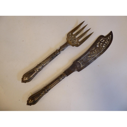 253 - An early Victorian silver fish slice and fork with decoratively pierced ornament, on moulded handles... 