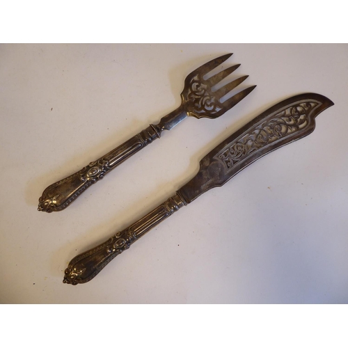 253 - An early Victorian silver fish slice and fork with decoratively pierced ornament, on moulded handles... 