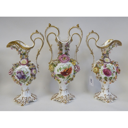 263 - A trio of late 19thC, possibly Coalbrookdale, china ewers of pedestal, bulbous form, painted, encrus... 