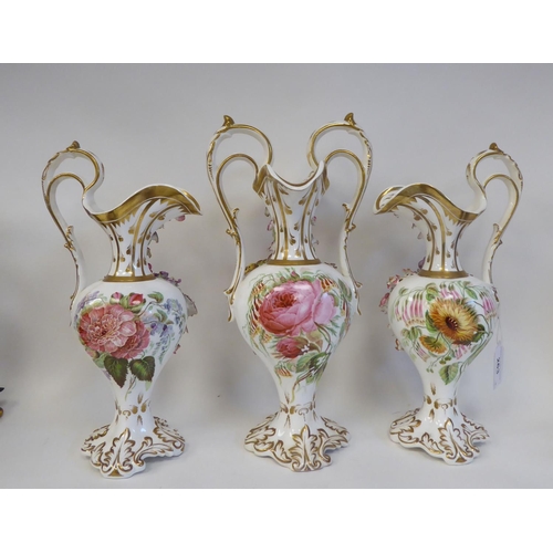 263 - A trio of late 19thC, possibly Coalbrookdale, china ewers of pedestal, bulbous form, painted, encrus... 