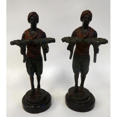 284 - A pair of late Victorian cold painted bronze standing figures, Arab servants, each holding two lotus... 