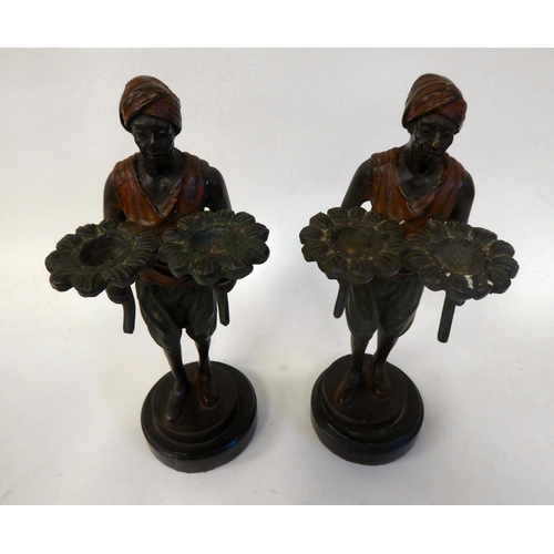 284 - A pair of late Victorian cold painted bronze standing figures, Arab servants, each holding two lotus... 