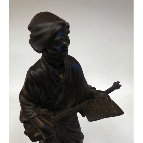 286 - A 19thC Japanese figure, an itinerant man playing a stringed instrument, whilst holding sheet music&... 