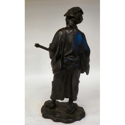 286 - A 19thC Japanese figure, an itinerant man playing a stringed instrument, whilst holding sheet music&... 