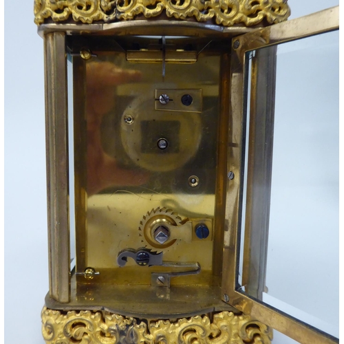 288 - A mid 20thC gilt metal cased carriage timepiece with decoratively cast frieze ornament, beaded glass... 