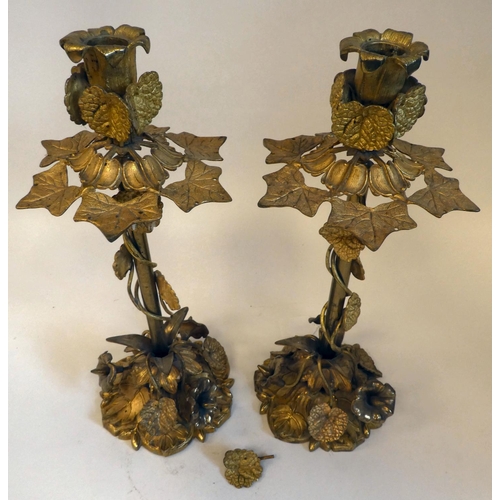 43 - A pair of late Victorian gilded metal, naturalistically formed candlesticks, adorned with trailing a... 