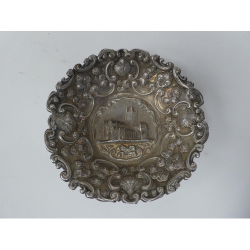 57 - A silver dish, featuring an embossed elevation of a church, the borders depicting sea scrolls, shell... 