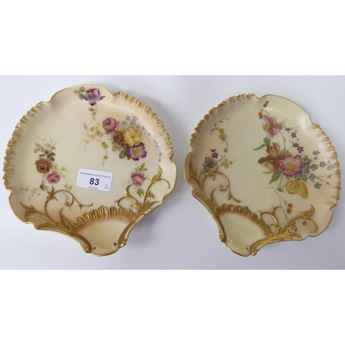 83 - A pair of Royal Worcester blush ivory glazed and gilded china scallop shape dishes, decorated with f... 