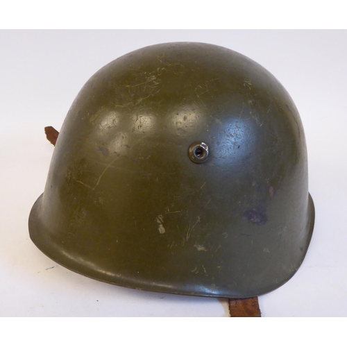 87 - A German World War II era, khaki painted military helmet with a hide liner and buckled chinstrap(Ple... 